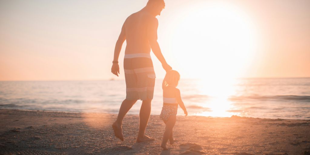 man holding girl heading towards sea