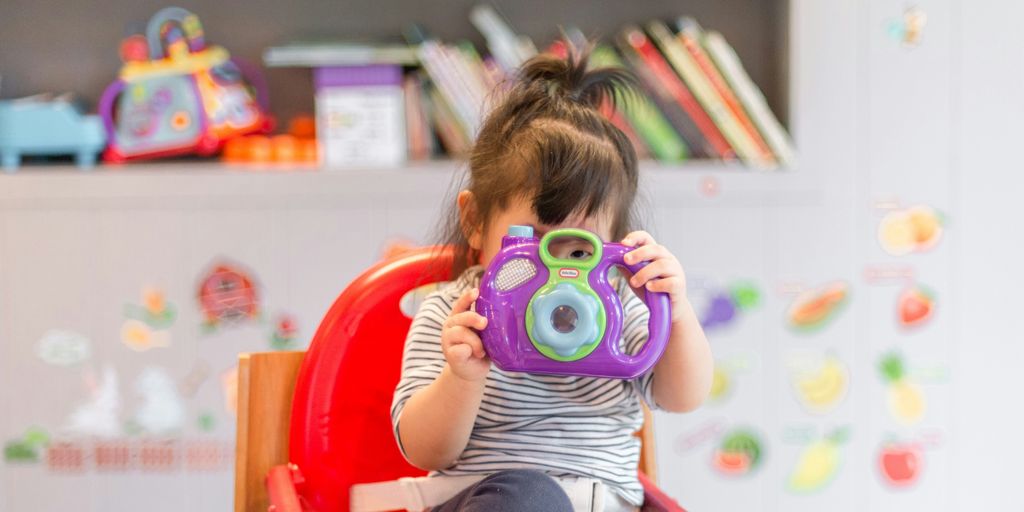 girl holding purple and green camera toy