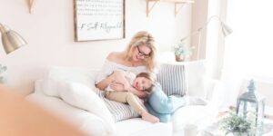 woman and baby sitting on white sofa